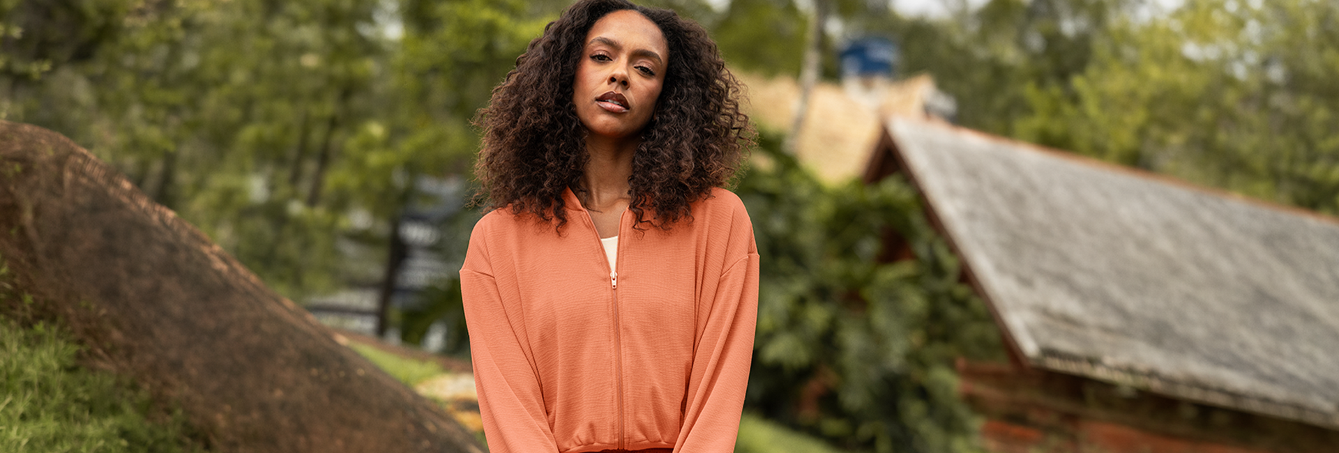person with curly hair wearing an orange jacket outdoors